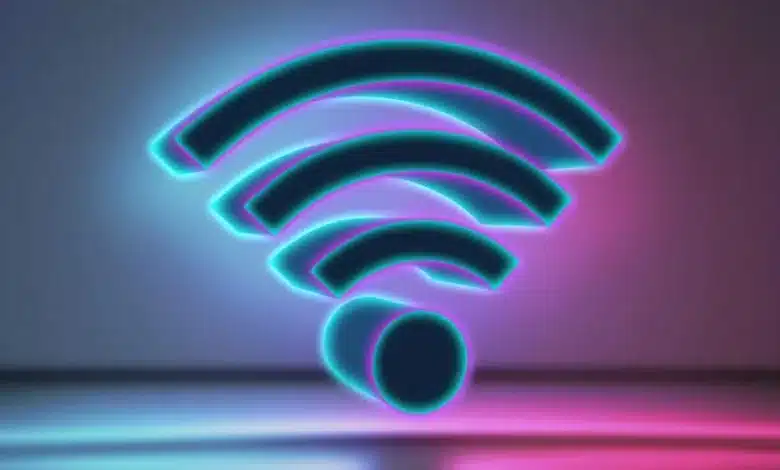 Un symbole Wi-Fi lumineux avec un contour bleu fluo sur un fond violet et rose flou. Le symbole projette un léger reflet sur la surface en dessous.