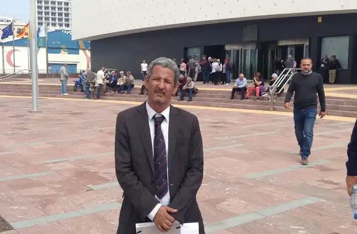 Ahmed Ould Bettar en costume, tenant des documents, debout devant le centre Poema del Mar à Las Palmas
