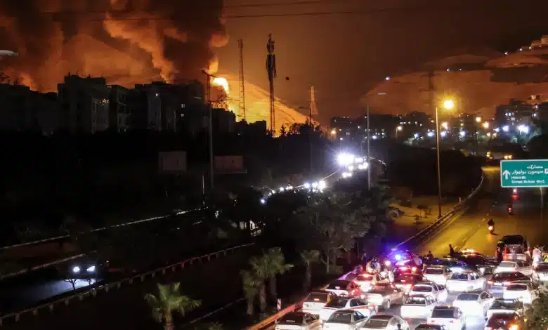 Des voitures tentent d'emprunter l'autoroute alors qu'un incendie se déclare dans des dépôts pétroliers à Shahran, au nord-ouest de Téhéran, après des frappes israéliennes.