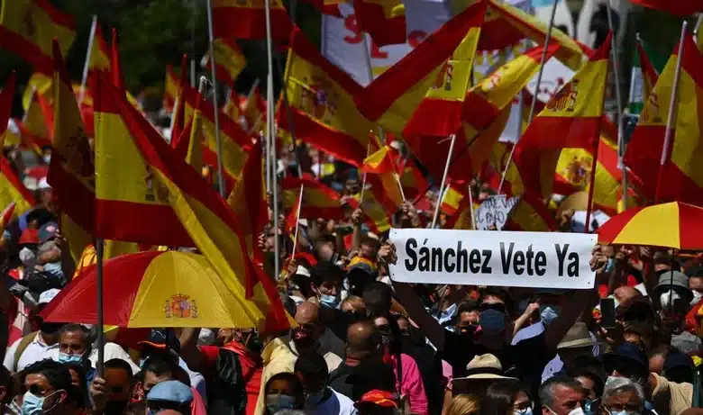 Manifestants à Madrid brandissant des drapeaux espagnols et une pancarte « Sánchez vete ya »
