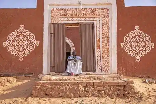 Vieil homme assis devant une porte ornée à Oualata, ville classée au patrimoine mondial de l’UNESCO en Mauritanie