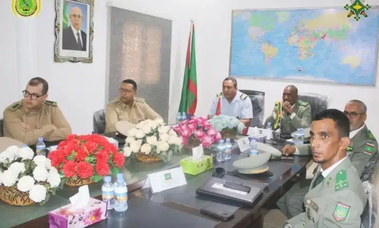 réunion des officiers militaires autour d'une table avec des fleurs et une carte du monde en arrière-plan..webp