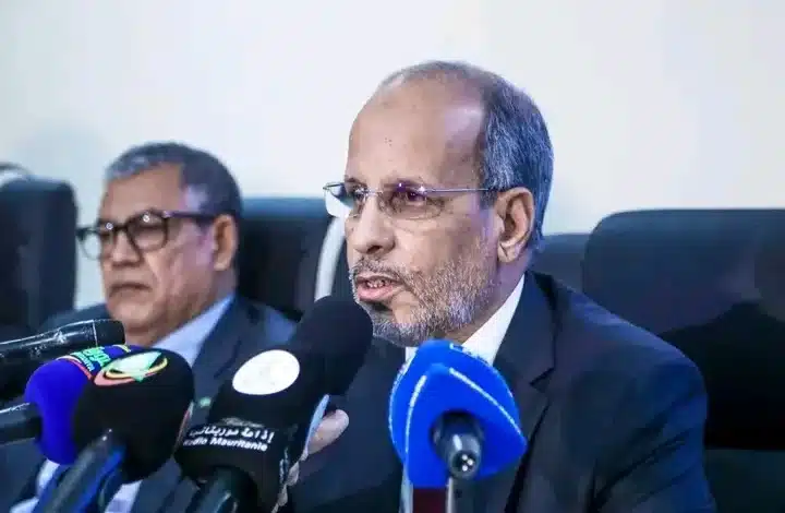 Mohamed Maelainine Ould Eyih s’exprimant lors d’une conférence de presse entouré de micros de presse locale.
