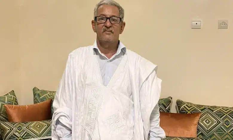 Portrait d’Ahmed Ould Bettar en boubou blanc, dans un salon mauritanien traditionnel.