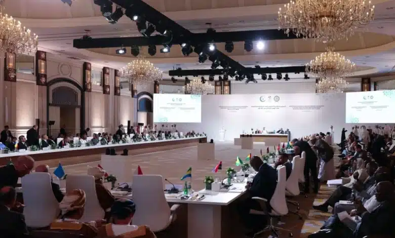 Salle de conférence à Doha accueillant le sommet arabo-islamique d’urgence, avec les dirigeants réunis autour d’une grande table en U sous de grands lustres.