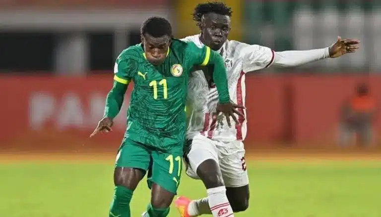 Les joueurs du Sénégal et du Soudan s'affrontent lors d'un match de qualification pour la Coupe du monde. Le joueur n° 11 du Soudan est visible.