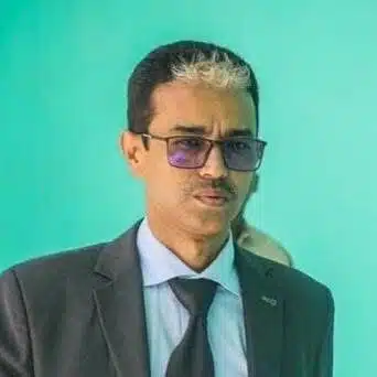 Portrait d’un homme en costume et lunettes, sur fond vert, illustrant un article sur la gouvernance et la lutte contre la corruption en Mauritanie.