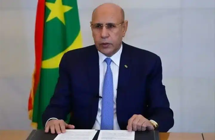 Le président mauritanien Mohamed Ould Cheikh El Ghazouani lors d’une allocution officielle à Nouakchott, avec le drapeau national en arrière-plan.