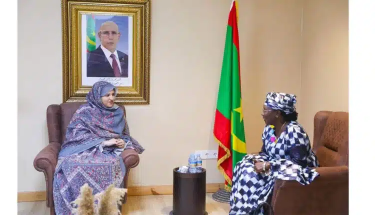 Deux responsables en réunion dans un bureau officiel à Nouakchott, assises face à face, avec un drapeau mauritanien et un portrait présidentiel en arrière-plan.