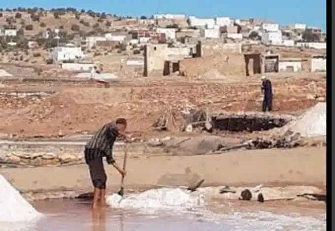 Travailleur récoltant le sel dans les salines de Dar Beyda, entourées de déchets et de zones polluées.