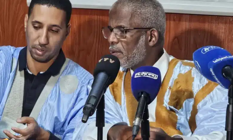 Deux intervenants en boubou traditionnel mauritanien parlent devant des micros de presse lors d’un point de presse.