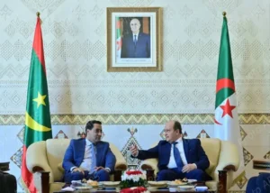Diplomatie mauritanienne : L'équilibre subtil entre Alger et Rabat | Rapide Info 2 Le Premier ministre mauritanien Mokhtar Ould Djay s'entretenant avec un responsable algérien à Alger, encadré par les drapeaux des deux pays.
