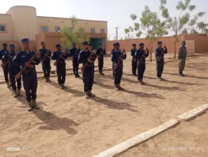 Le Groupement Régional N°4 célèbre le 114e anniversaire de la Garde Nationale 2 Section de gardes nationaux mauritaniens en uniforme bleu foncé effectuant un salut armé lors de la levée des couleurs à la cérémonie du GR4 à Aleg.