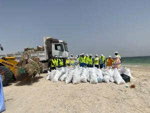Environnement : la SNIM et les associations locales s’unissent pour assainir le littoral de Cansado 5 Vue d'ensemble sur la plage montrant des montagnes de sacs plastiques remplis et des engins en charge de l'évacuation.