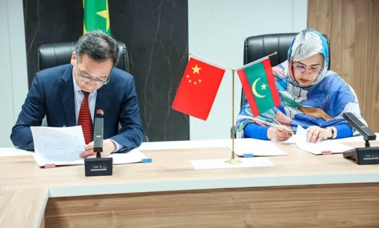 Extension de l'Hôpital de l'Amitié : Signature d'un accord Mauritanie-Chine 1 Mme El Aliya Yahya Menkouss et le représentant chinois signant la convention d'extension de l'Hôpital de l'Amitié sous les drapeaux mauritanien et chinois.