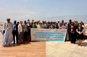 Femmes et foi : Prévenir l'extrémisme en Afrique de l'Ouest 2 Participants posant derrière une banderole de l'Atelier régional sur le leadership religieux des femmes face à la mer à Dakar.