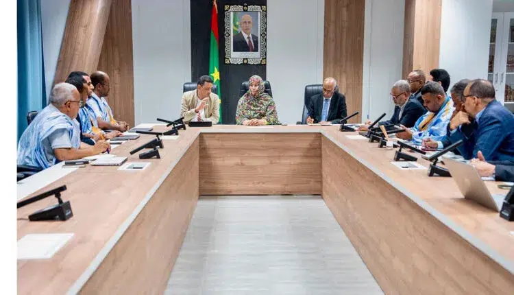 Nouakchott – La Santé et la Transformation numérique accélèrent la numérisation des nouveaux centres de santé 1 La ministre de la Santé Naha Mint Meknass et le ministre de la Transformation numérique Ahmed Salem Bouda Achvagha coprésident une réunion de travail autour d'une grande table de conférence.